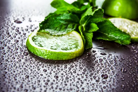 Zielone limonki z mieta i kroplami wody na czarnym tle